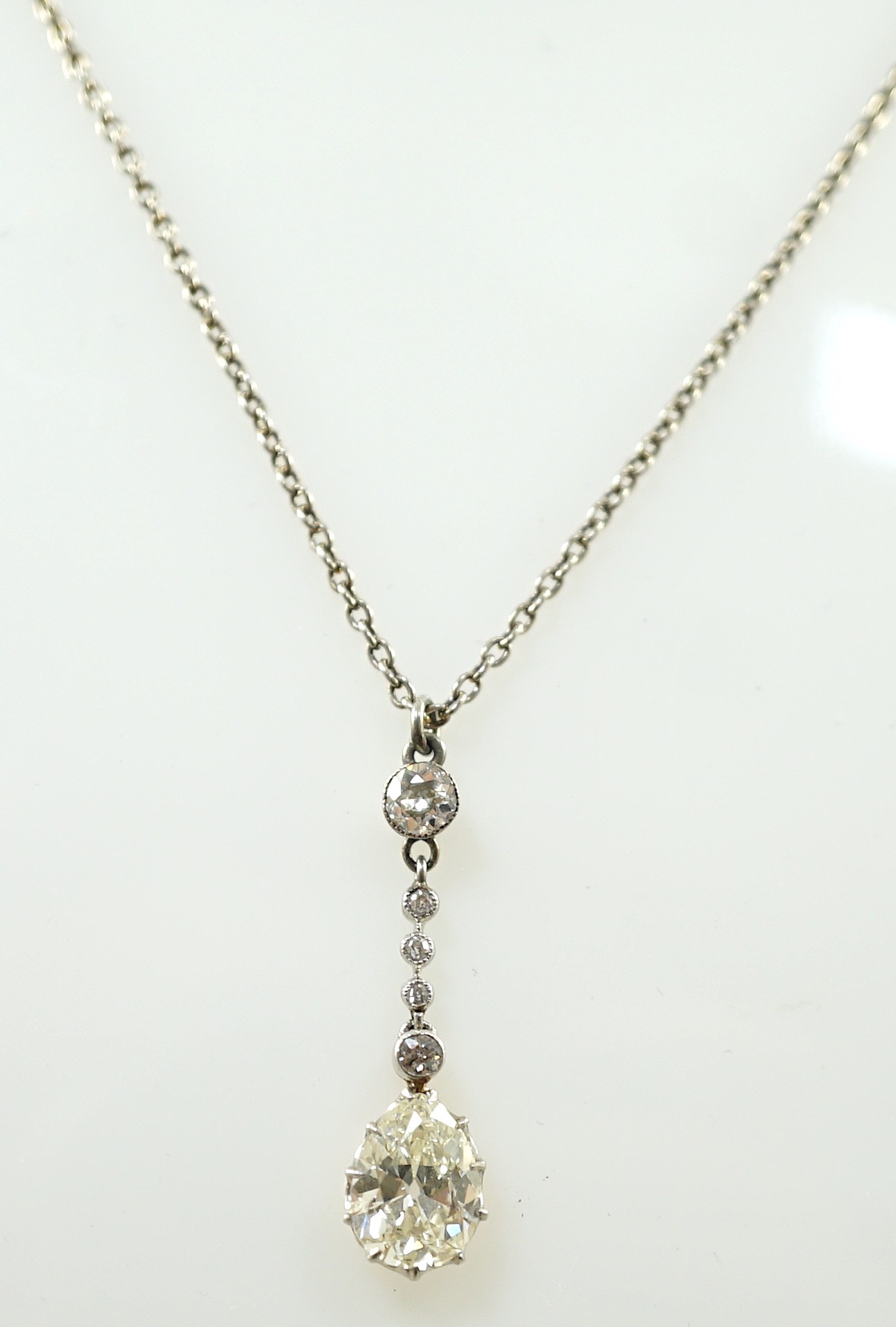 An early to mid 20th century white and yellow gold, six stone diamond set drop pendant, on a white gold chain, the clasp stamped 9k
